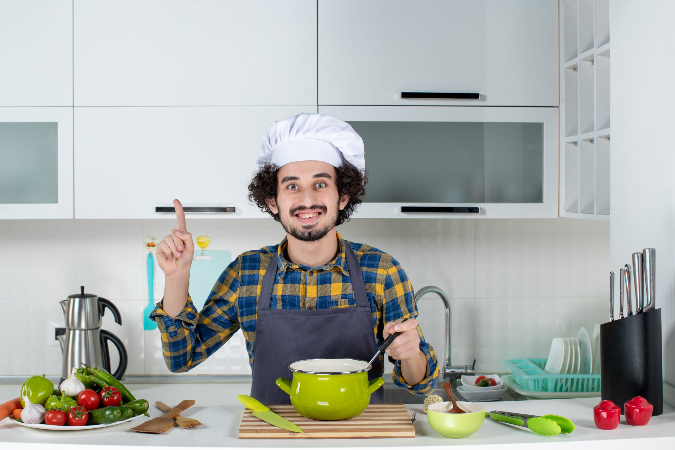 front-view-smiling-male-chef-with-fresh-vegetables-tasting-ready-meal-pointing-up-white-kitchen front-view-smiling-male-chef-with-fresh-vegetables-tasting-ready-meal-pointing-up-white-kitchen